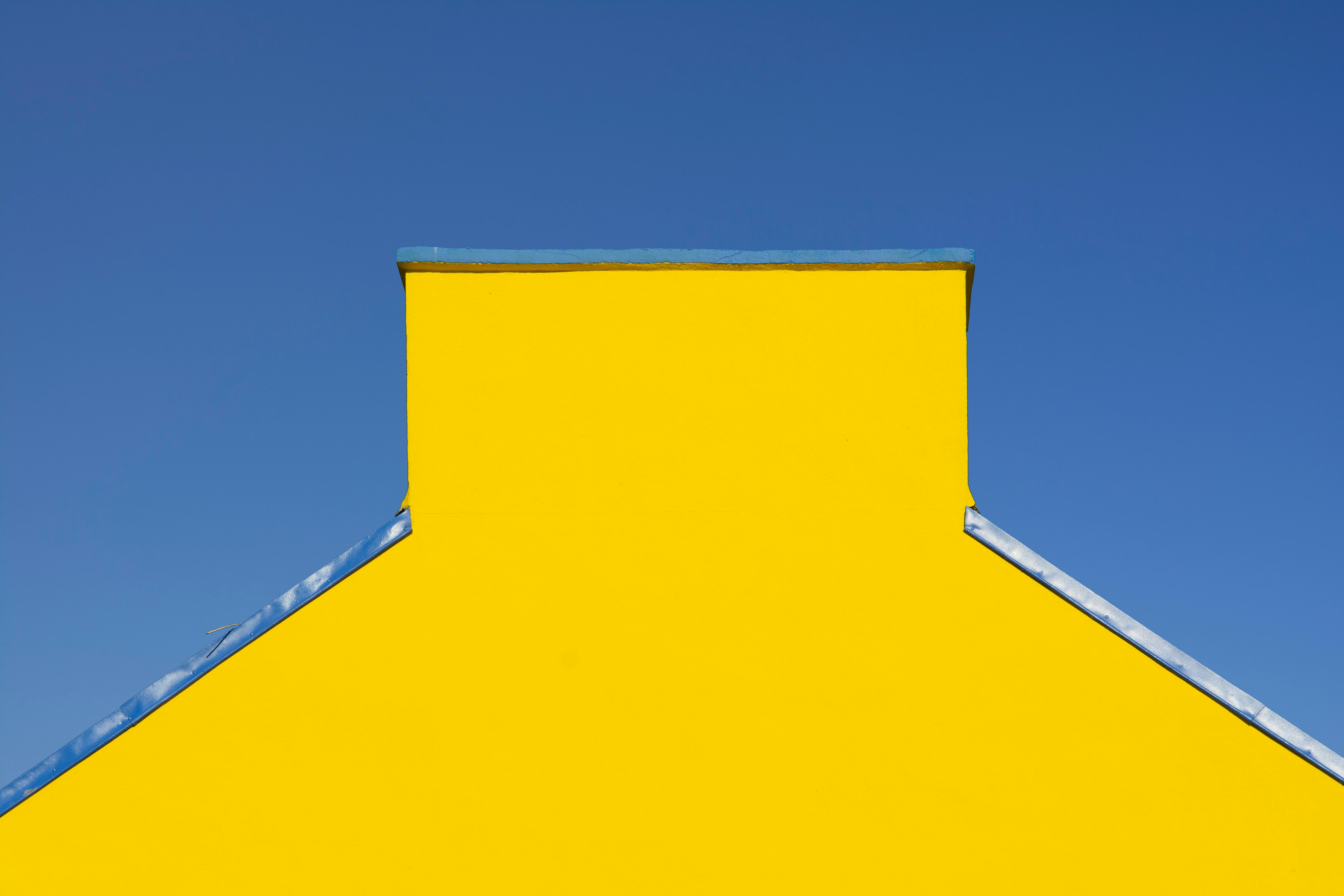 Gratis Levende gult hus med blåt tag mod klar himmel, der viser moderne arkitektur. Lagerfoto