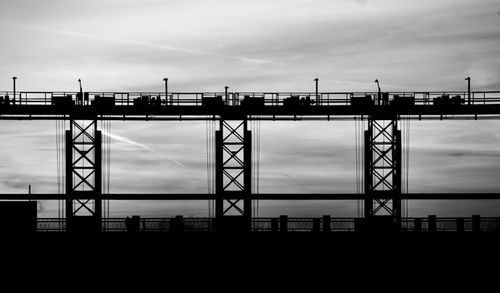 Free Artistic black and white silhouette of an industrial bridge structure against the cloudy sky. Stock Photo