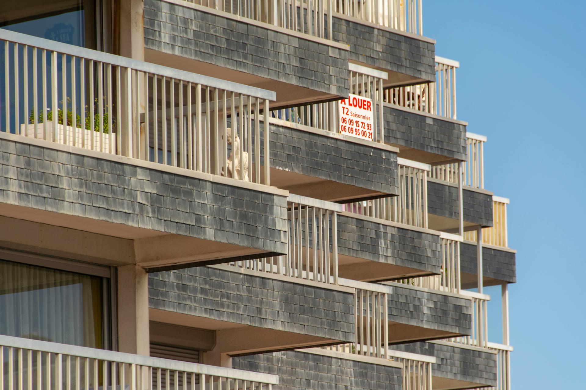 Close-up of modern building balconies with a visible rental sign.