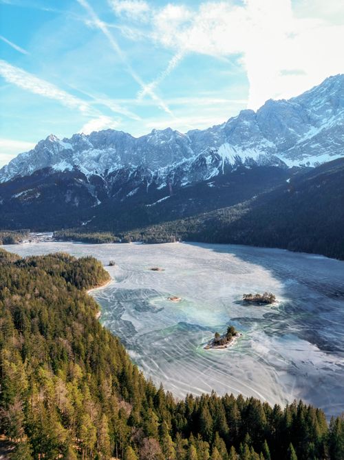Free A stunning aerial view of a frozen lake surrounded by snow-capped mountains. Stock Photo