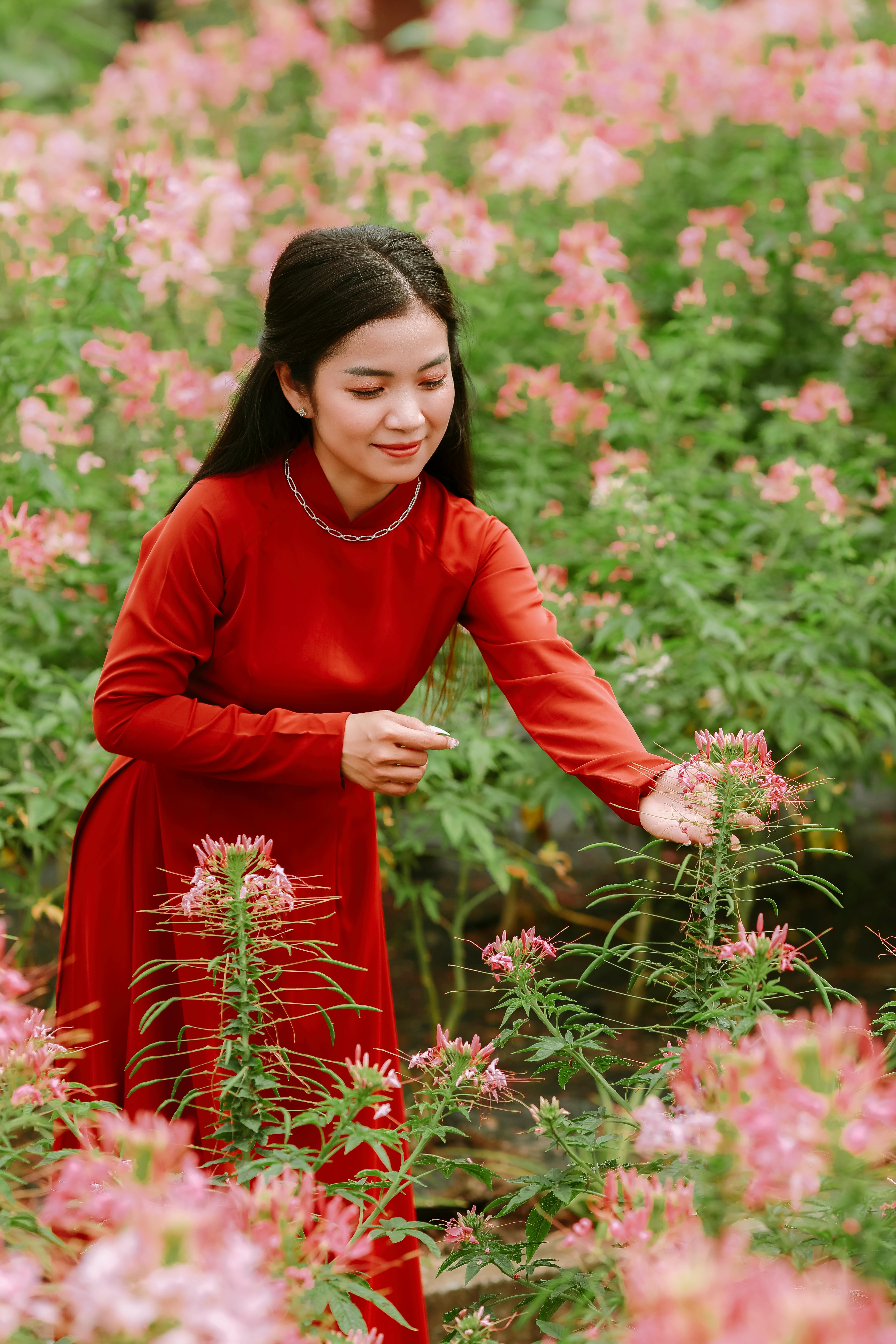 A woman in a red dress enjoys a vibrant flower field.
