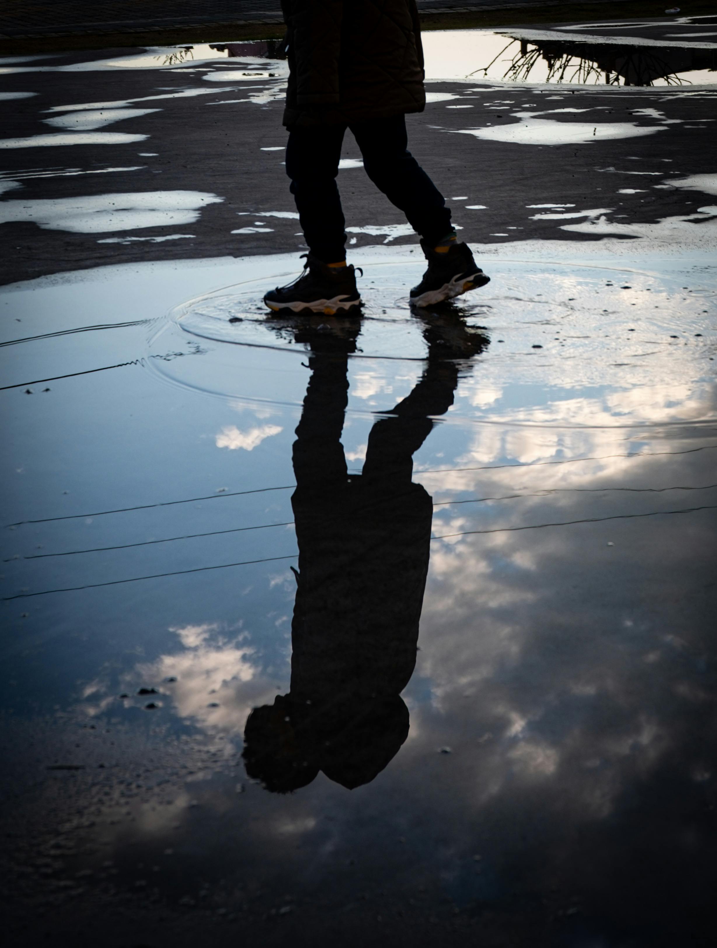 Silhouette Reflection in Rainy Puddle at Dusk · Free Stock Photo