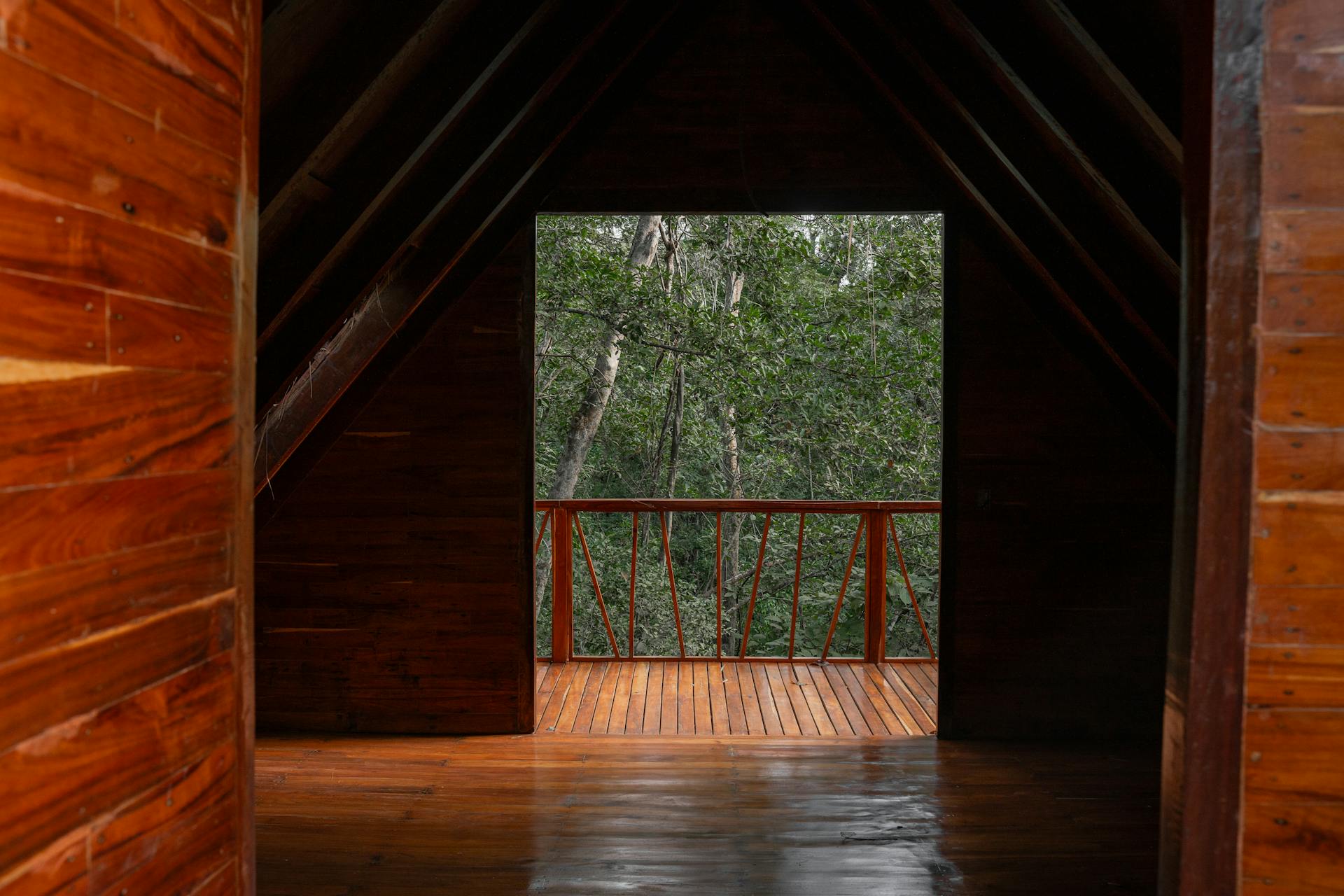 A tranquil wooden cabin interior leading to a forest-view balcony, ideal for nature retreat.