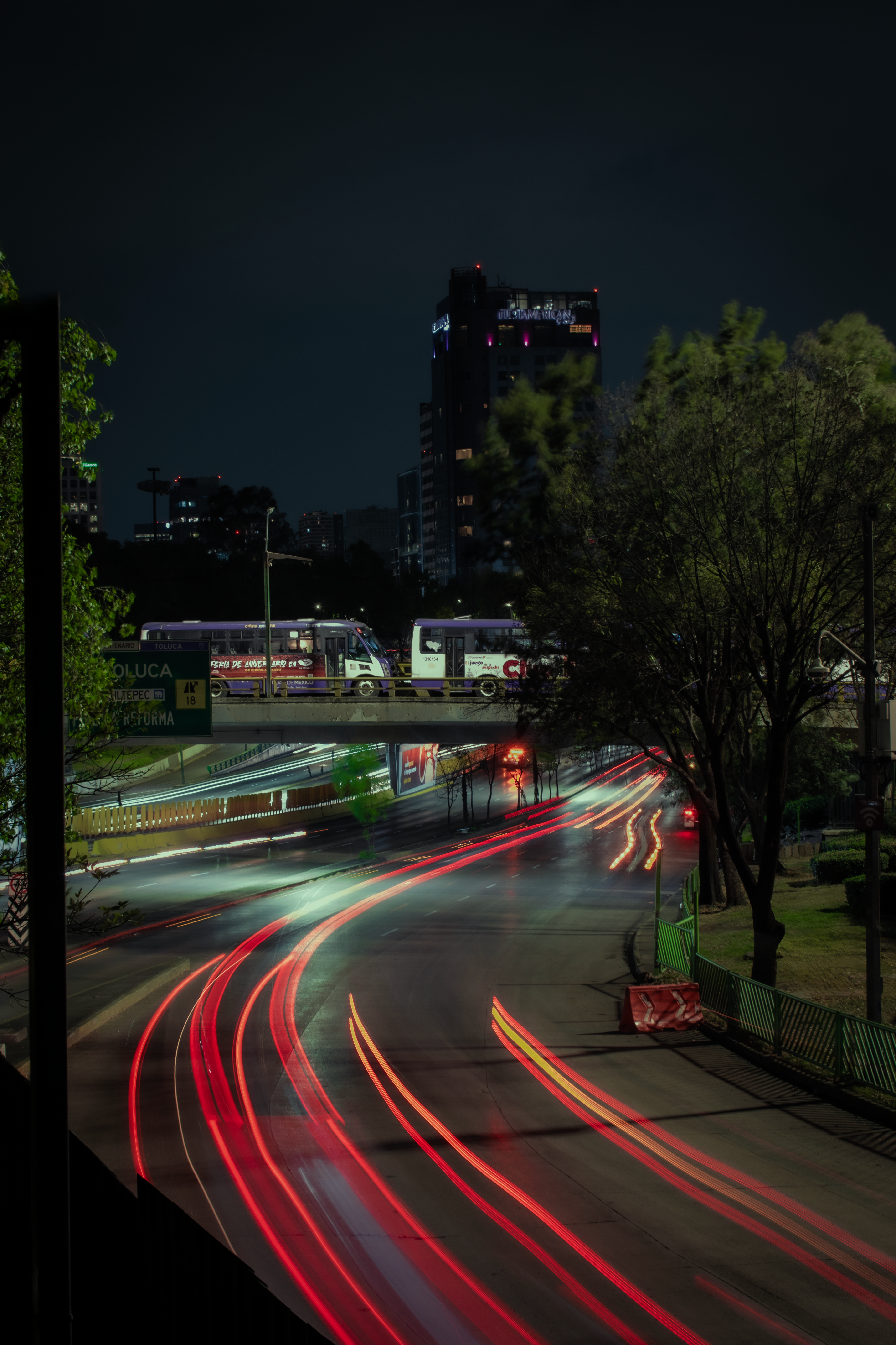 Vibrant city nightlife captured with light trails and urban skyline.