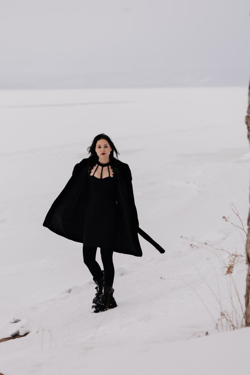 Elegant woman in black coat walking through snow