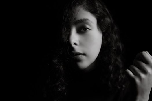 Dramatic black and white portrait of a woman with curly hair, capturing emotions.