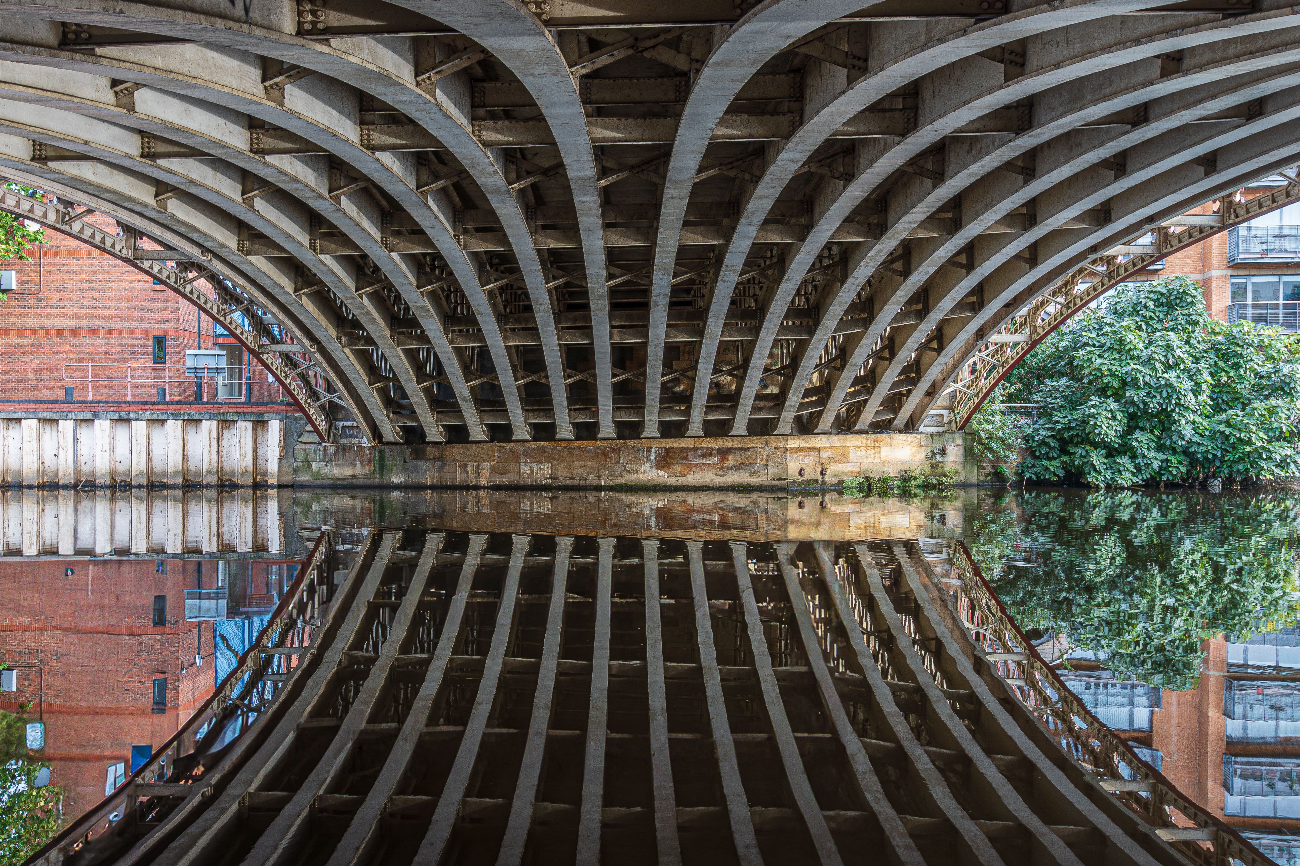 A stunning arched bridge reflecting symmetrically in the calm canal waters in Leeds, UK.