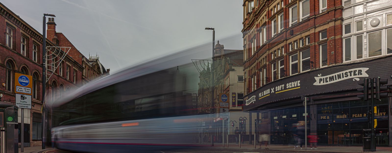 Long exposure of a bus creating motion blur in Leeds city center, highlighting historic architecture.