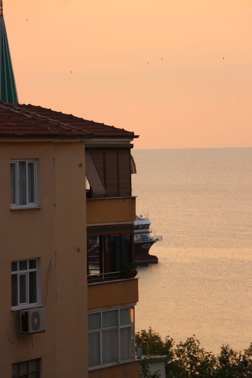 Free A serene sunset view with a building and sea, capturing tranquility and urban scenery. Stock Photo