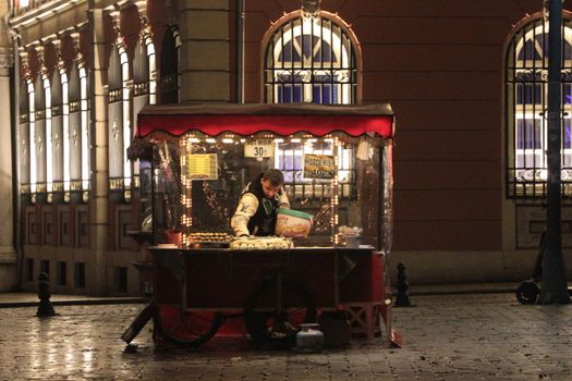 A night scene capturing a street vendor selling snacks in a vibrant city setting.