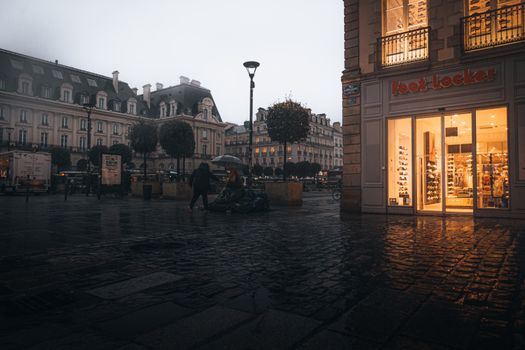 A captivating evening street view in Paris showcasing historic buildings and a bustling Foot Locker store.