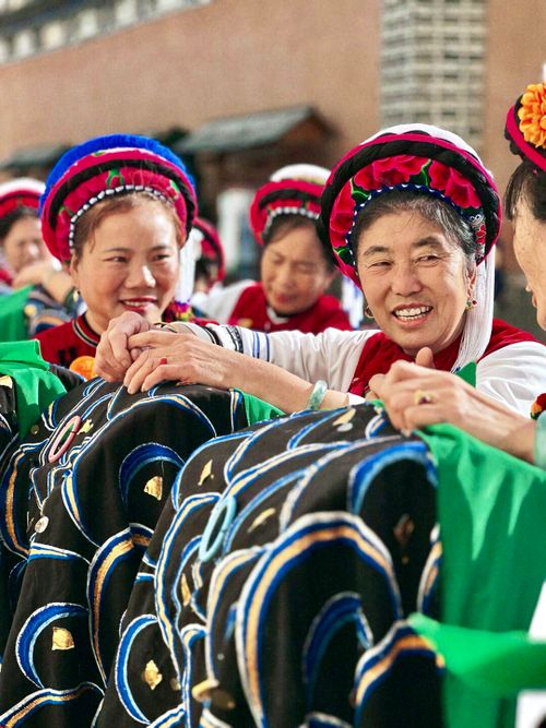 Free Women in vibrant traditional attire sharing joyful moments during a cultural event. Stock Photo