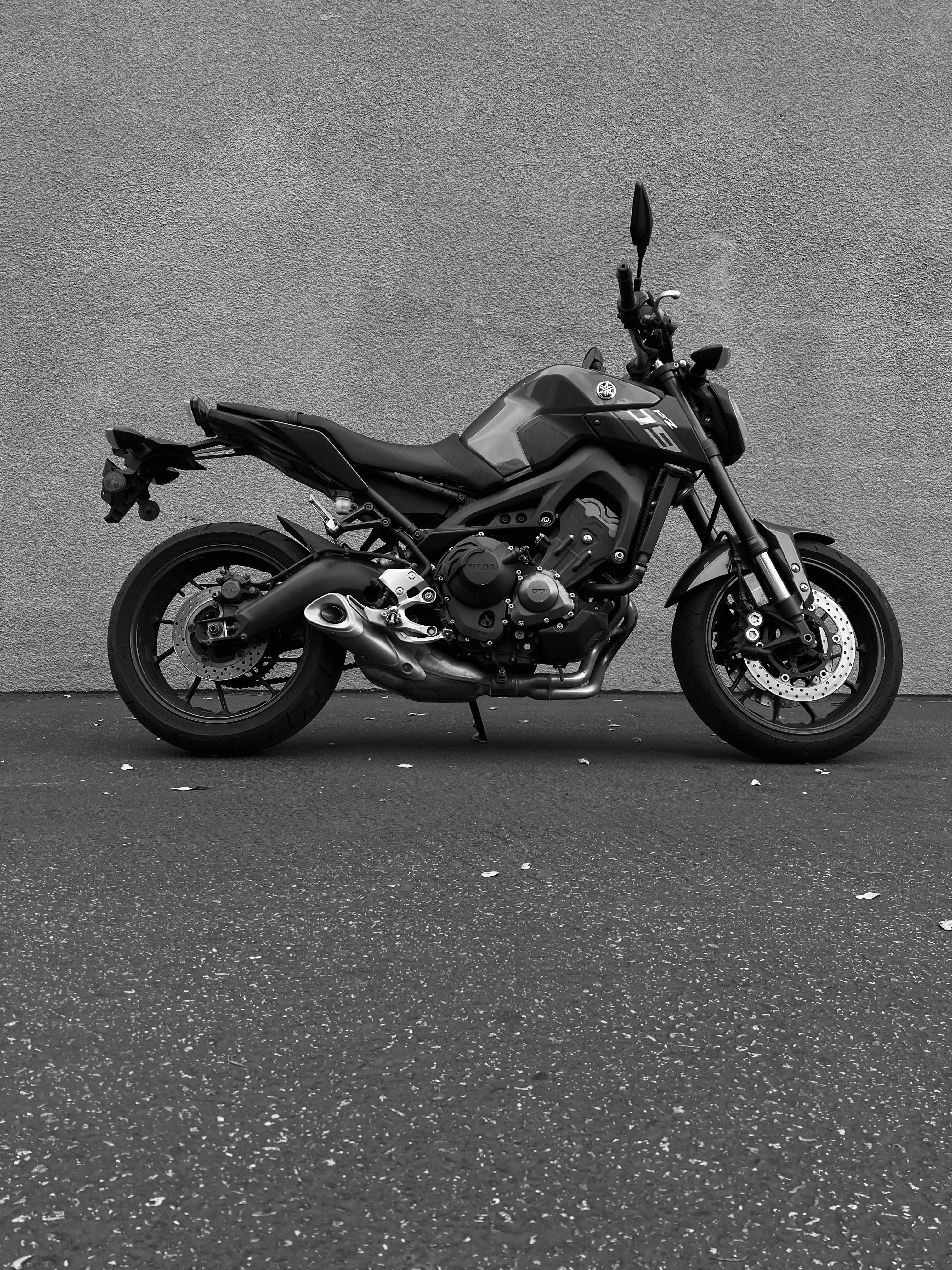 Free Black motorcycle parked against a plain wall, urban minimalist vibe. Stock Photo