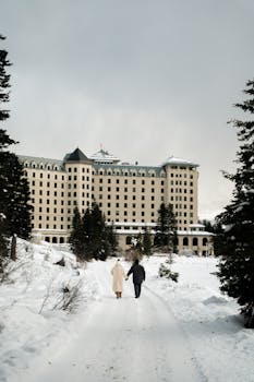 Couple walking in snowy landscape at Fairmont Chateau, Lake Louise, Canada.
