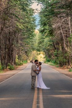 Couple shares a romantic kiss on a serene forest road in Bariloche, Argentina.