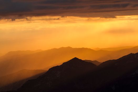 Stunning view of sunlit mountain ranges during a golden sunset, creating a serene ambiance.