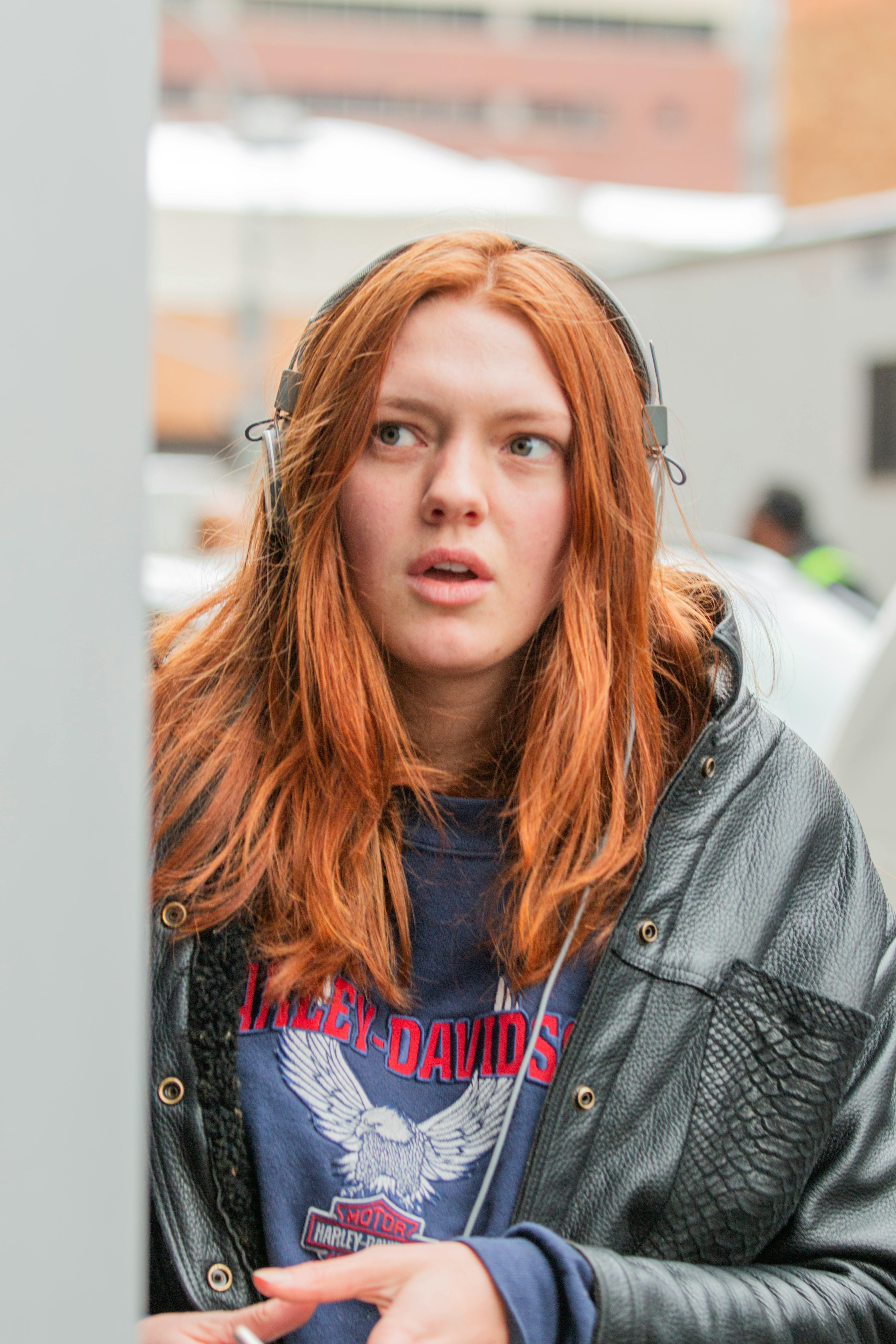 Bold fashion portrait of a woman in Harley-Davidson attire and leather jacket, embodying urban street style.