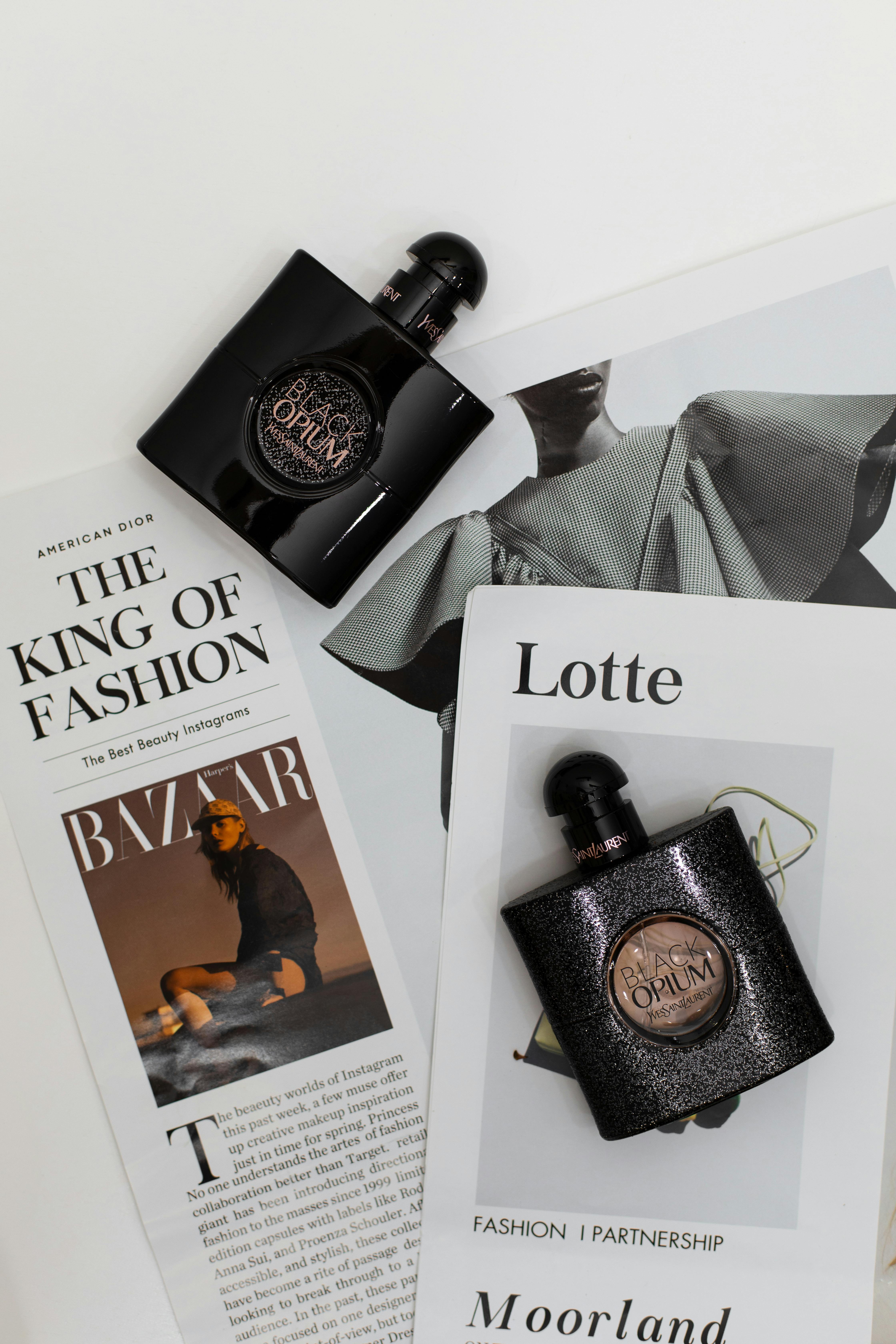 Elegant flat lay featuring Opium perfume bottles on fashion magazines. Perfect for luxury and style themes.