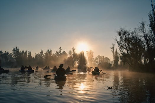 Silhouettes of kayakers paddling through Xochimilco canals at sunrise in Mexico City.