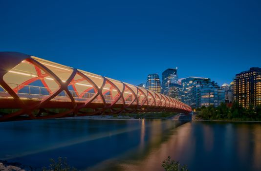 Stunning evening view of the illuminated Peace Bridge and Calgary skyline reflecting on the Bow River.