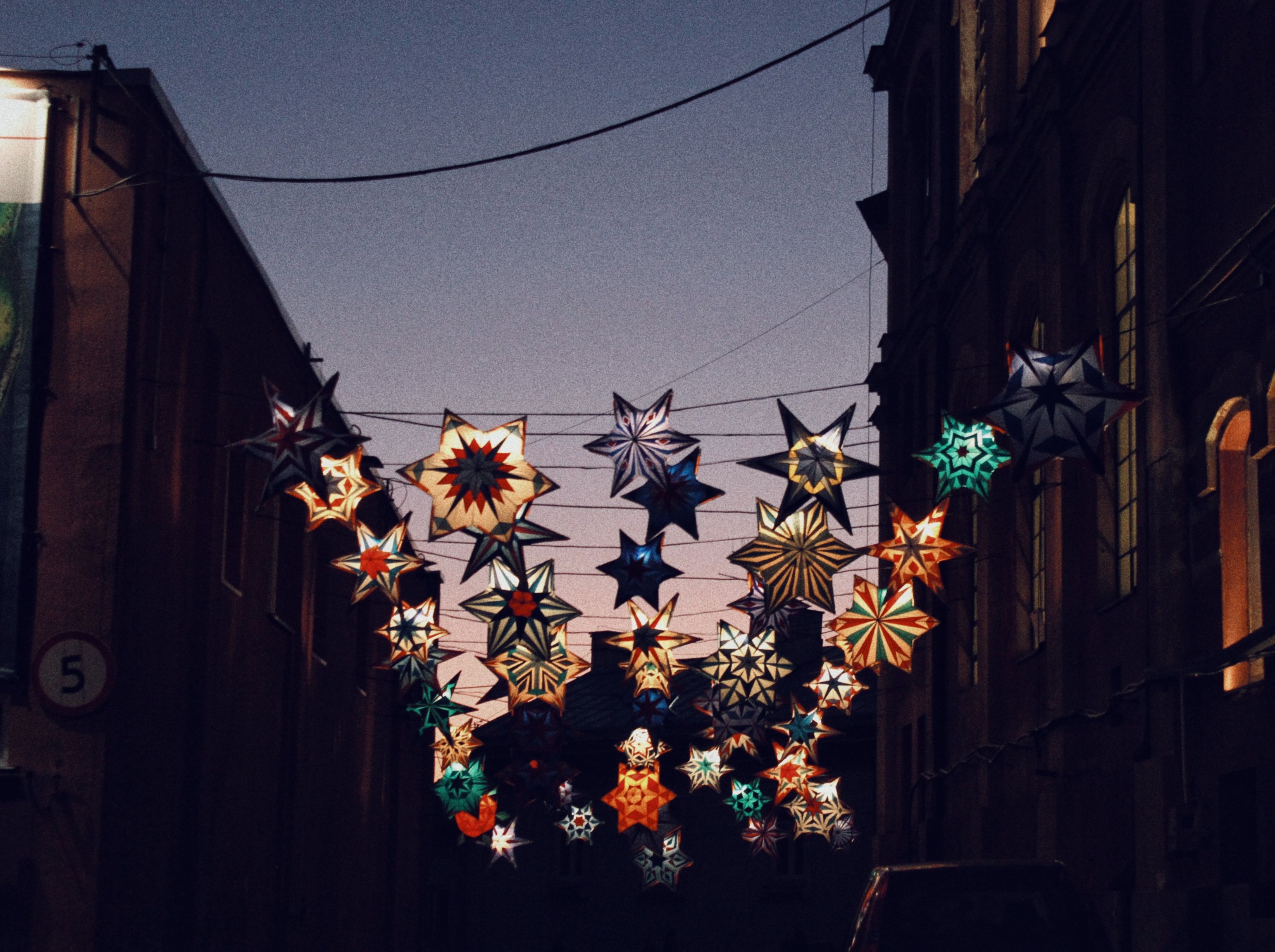 A vibrant display of star-shaped lanterns illuminating a street in Wrocław, Poland at night.