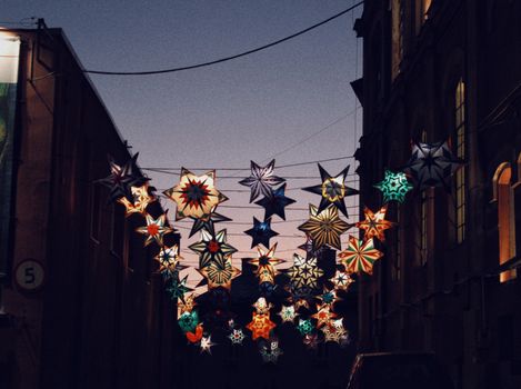 A vibrant display of star-shaped lanterns illuminating a street in Wrocław, Poland at night.