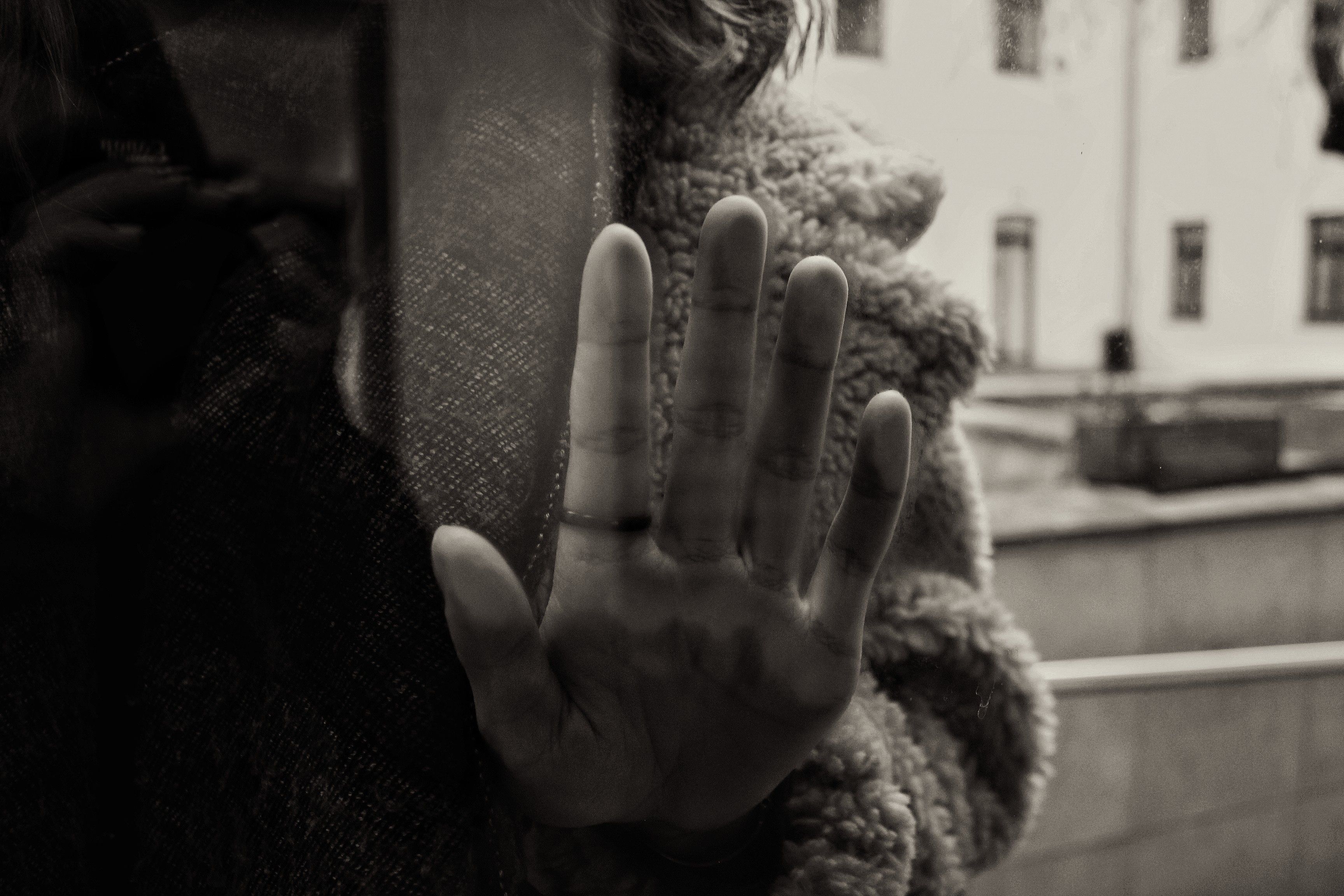 Gratuit Une photo en noir et blanc de mauvaise humeur d'une main touchant un verre avec un reflet. Photos