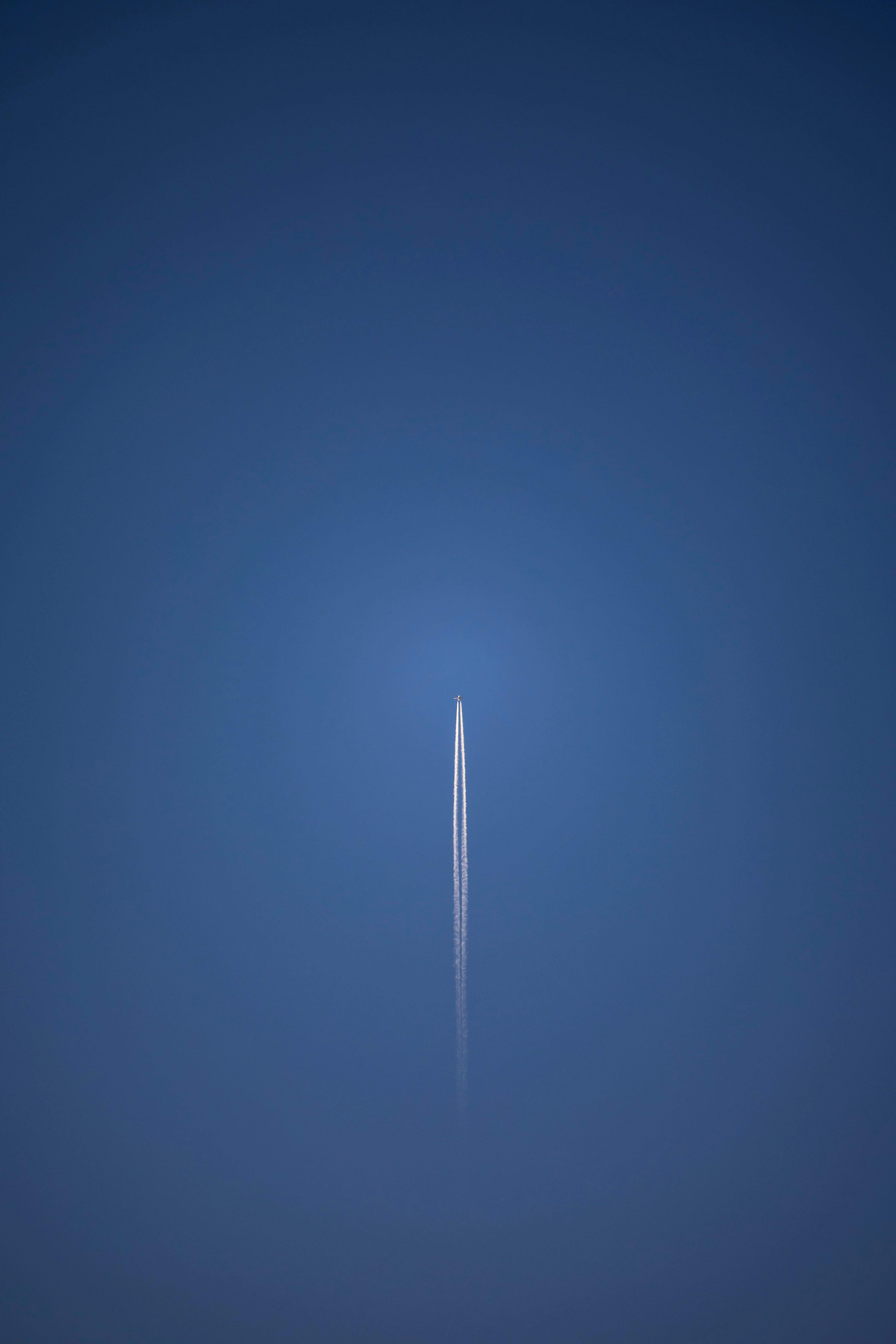 免費 一架高空飛行的噴射機在蔚藍的天空中留下長長的軌跡，象徵著旅行和探索。 圖庫相片