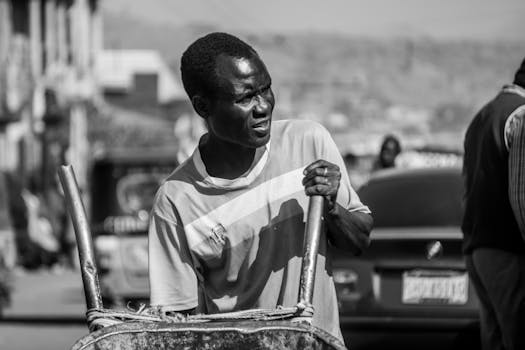 A striking black and white portrait of a man on a busy Nigerian street, capturing daily life.