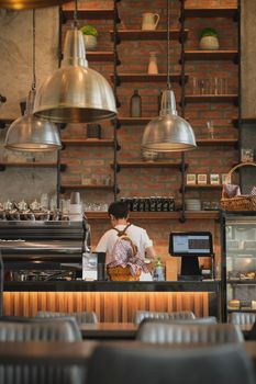 A modern cafe with a barista preparing coffee, warm lighting, and stylish decor.