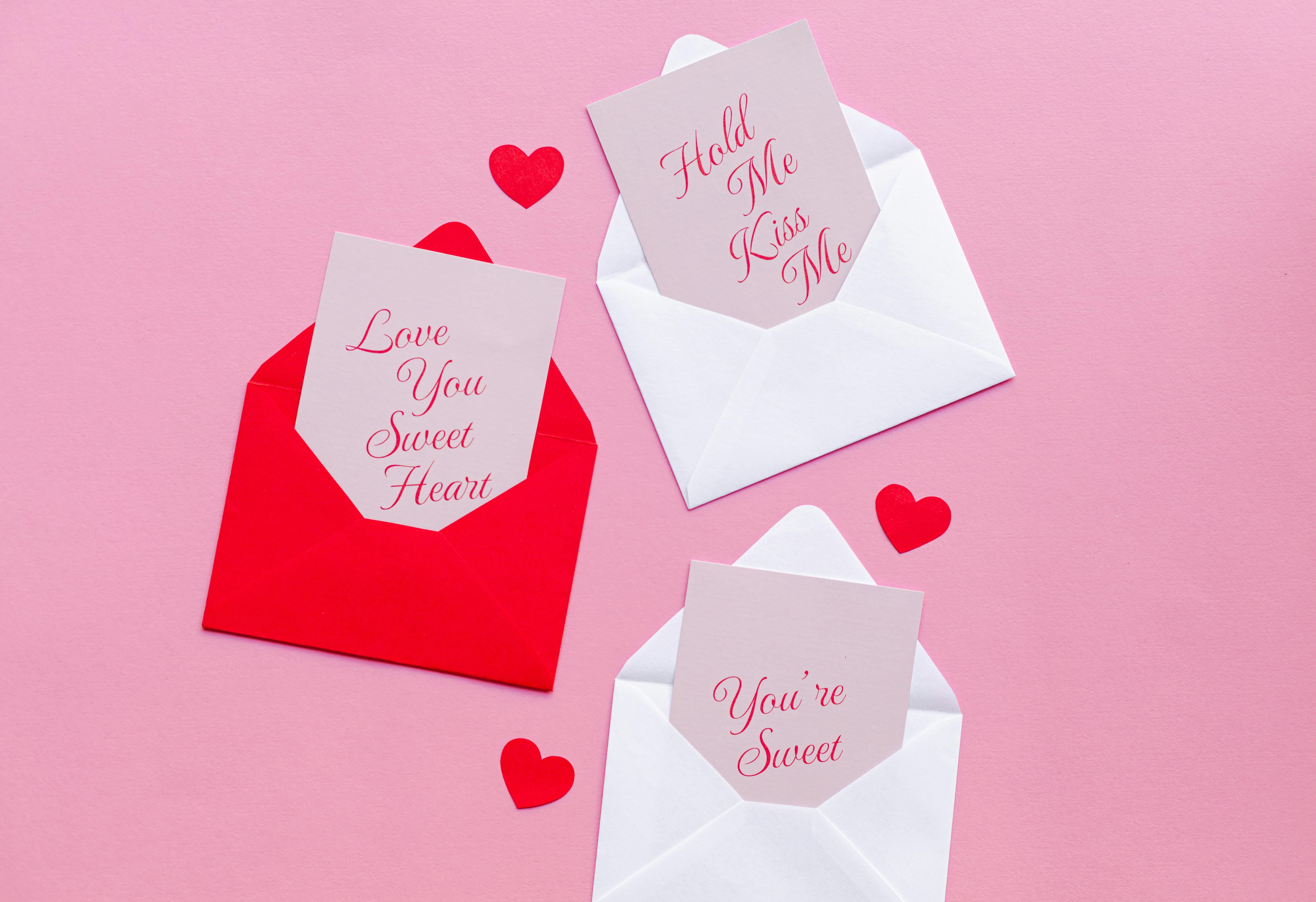 Red and white envelopes on pink background with romantic messages inside, perfect for Valentine's Day.