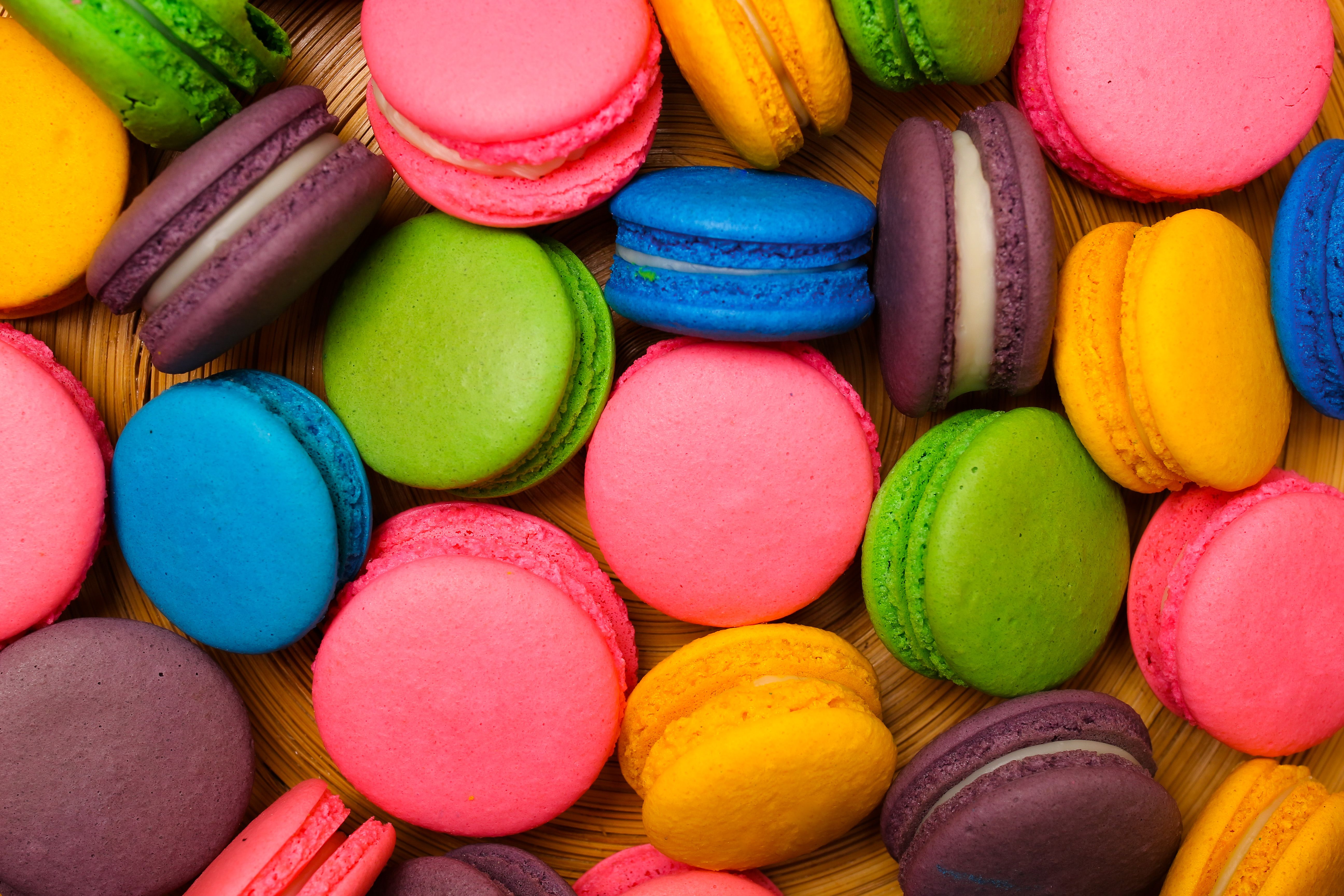 A vibrant assortment of French macarons in multiple colors on a wooden background.