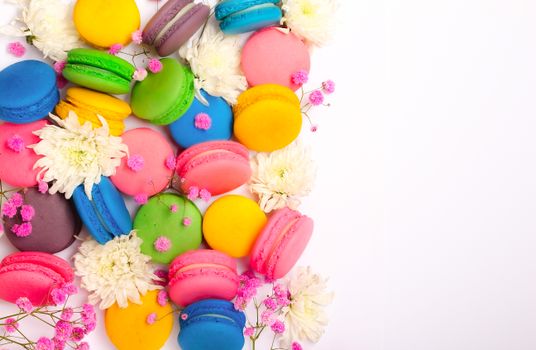 Vibrant macarons and fresh flowers on a white surface. Perfect for dessert themes.