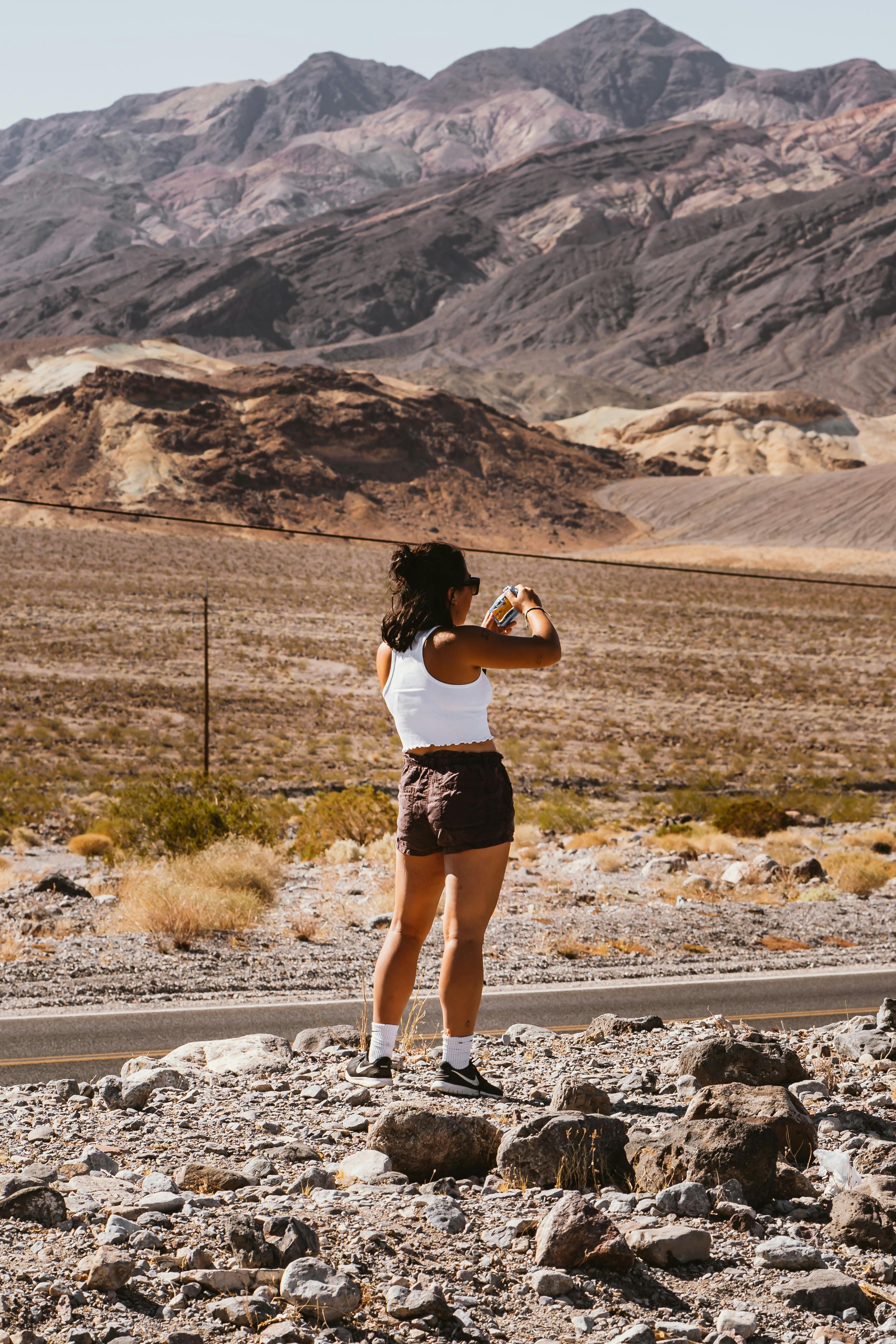 夏日明媚的阳光下，一名妇女拍摄了岩石沙漠景观的照片