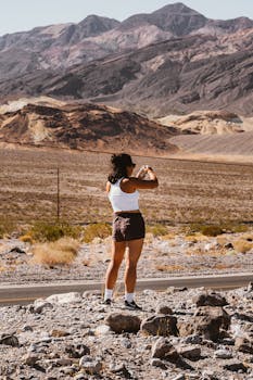 夏日明媚的阳光下，一名妇女拍摄了岩石沙漠景观的照片