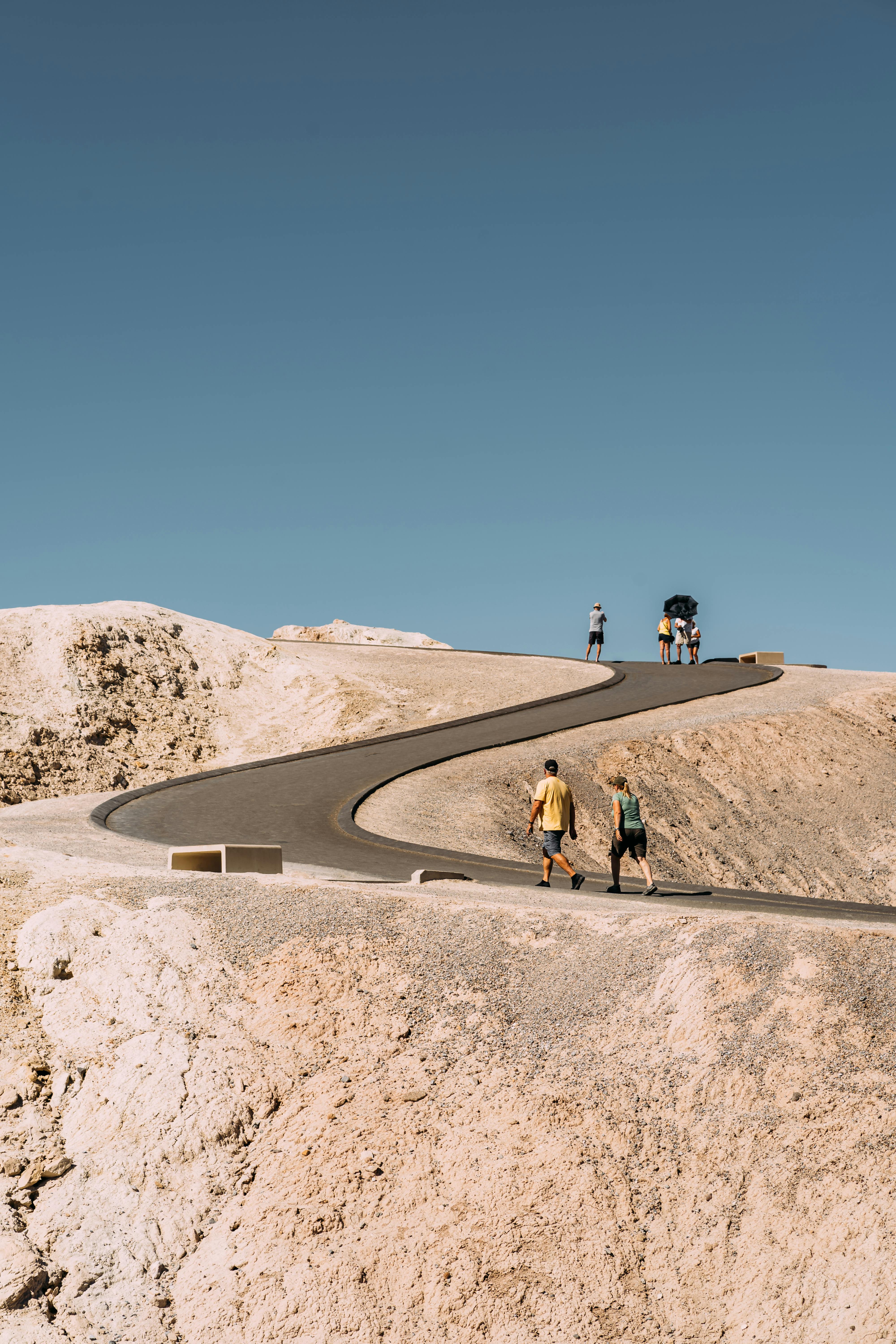 一群人走在蜿蜒的小路上，穿过阳光明媚的干旱沙漠