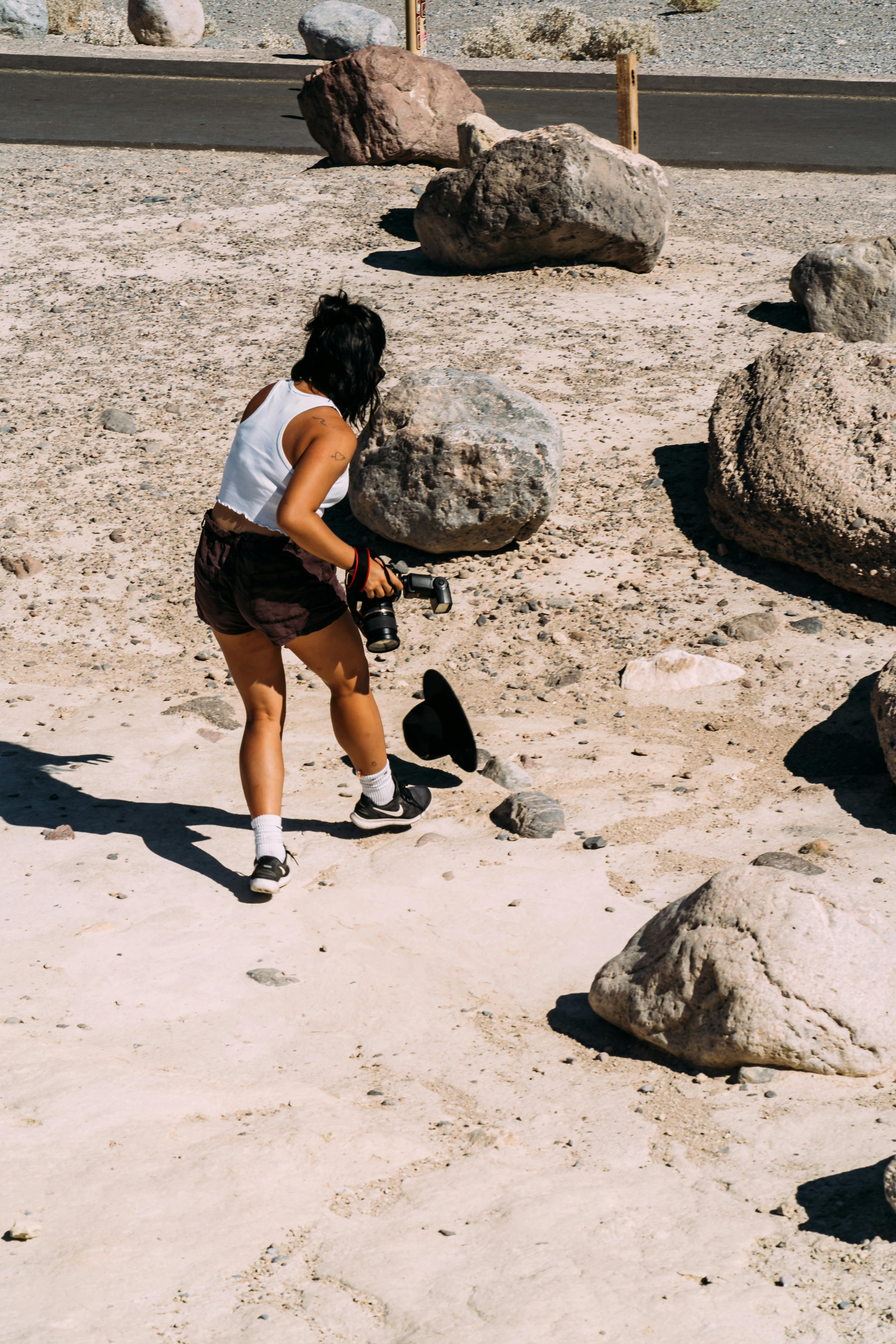女摄影师穿行于岩石沙漠之中，在明亮的日光下捕捉风景