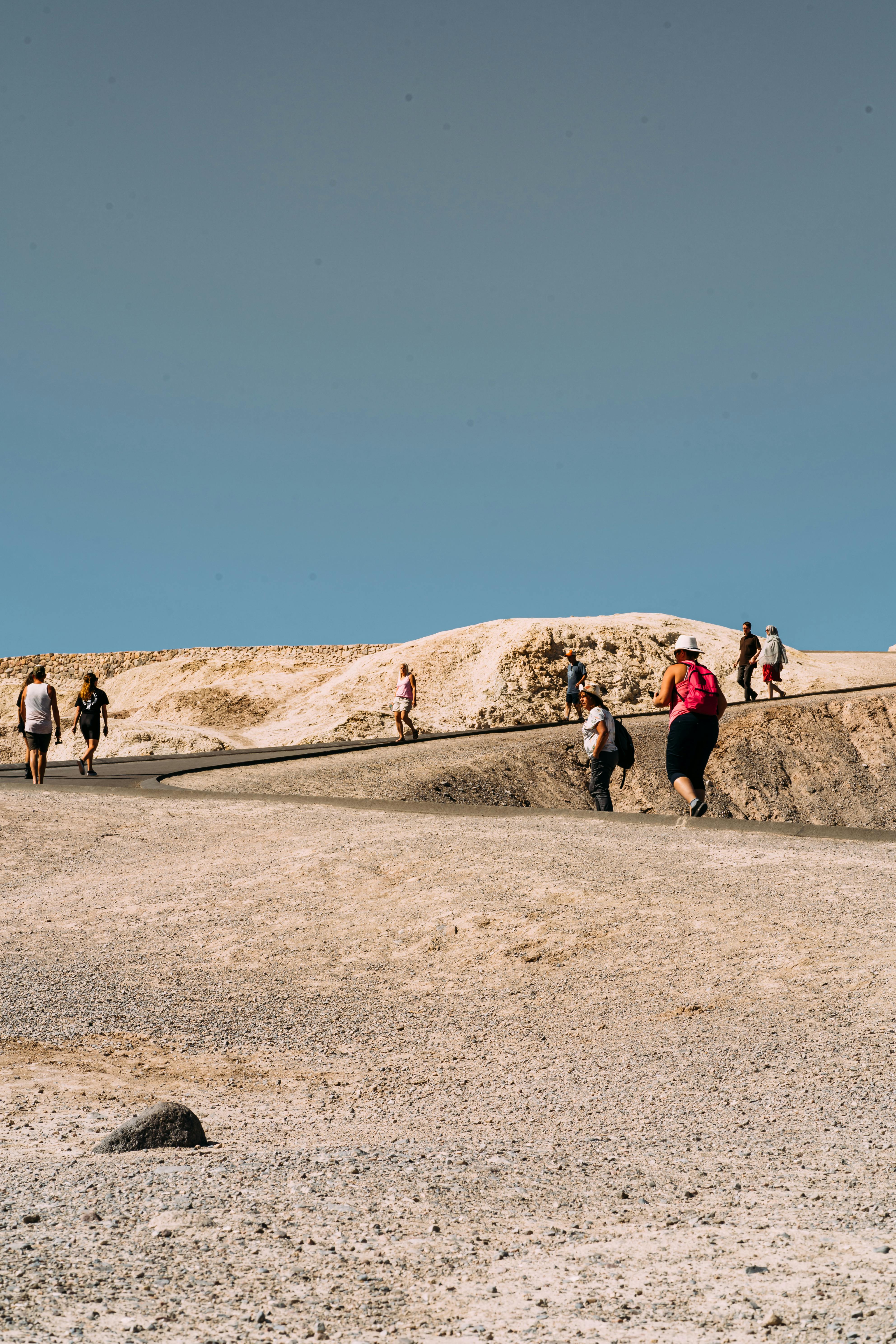 一群人在晴朗的天空下徒步穿越干旱的沙漠，捕捉冒险的本质