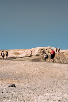 一群人在晴朗的天空下徒步穿越干旱的沙漠，捕捉冒险的本质
