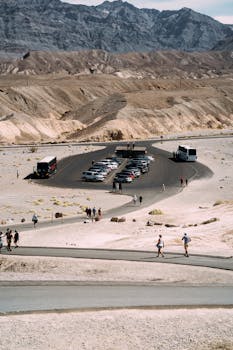 游客们在山区背景中，探索一个设有汽车和公共汽车的沙漠停车区