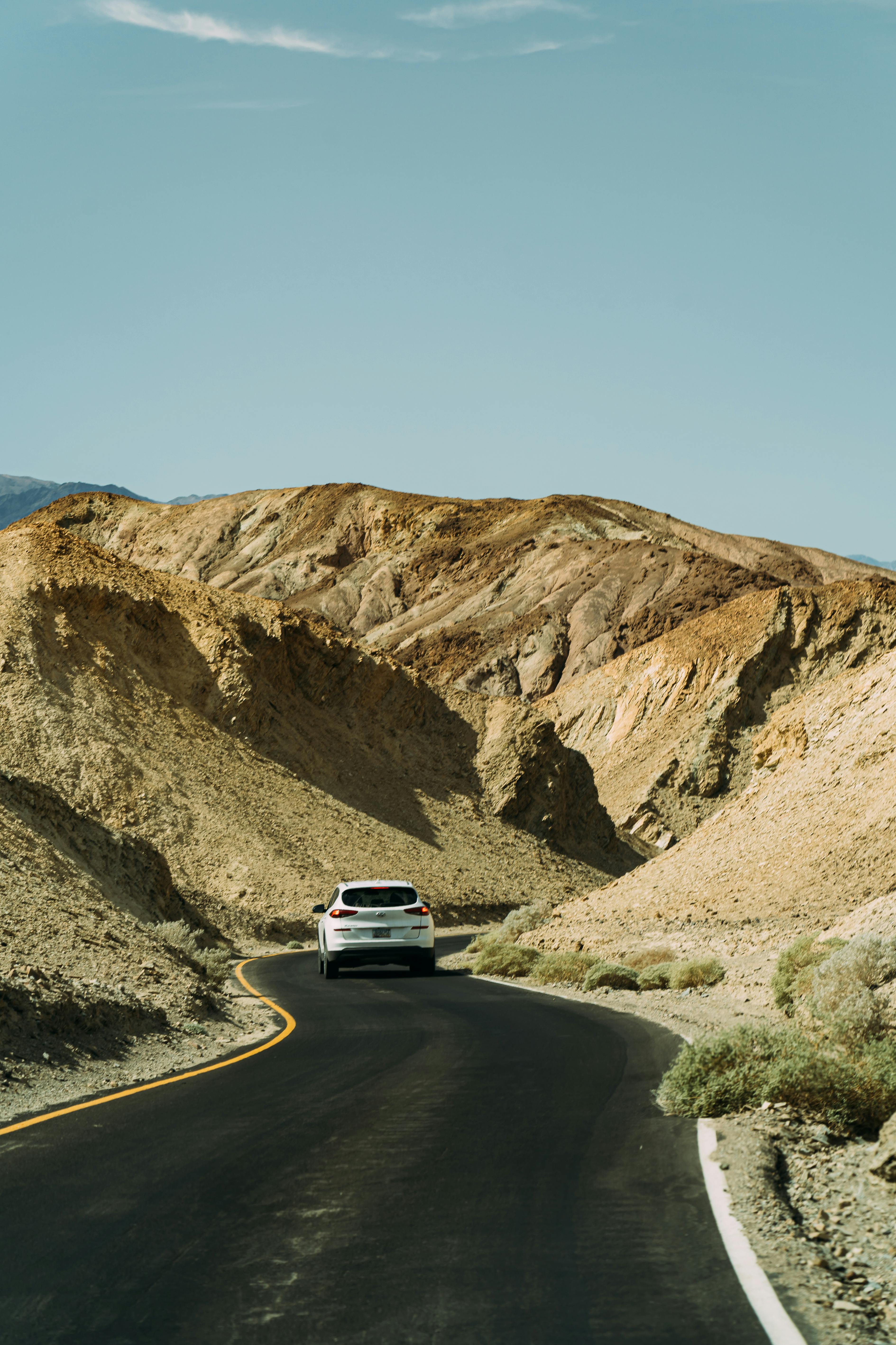 white car on road between rocks