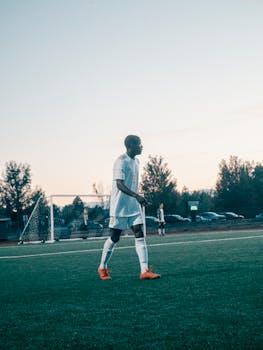 Teen soccer player in action on the field during dusk. Outdoor sports activity with goal visible.