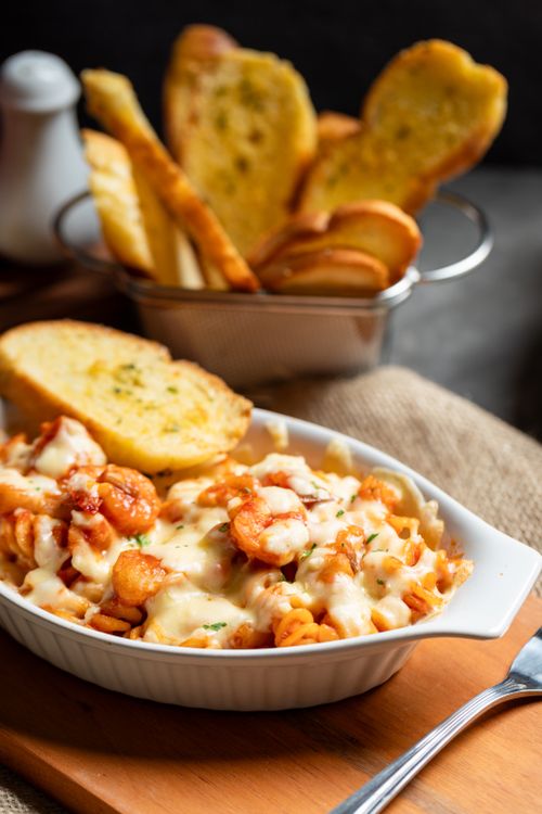 Free Creamy shrimp pasta dish with a side of golden garlic bread on a wooden board. Stock Photo