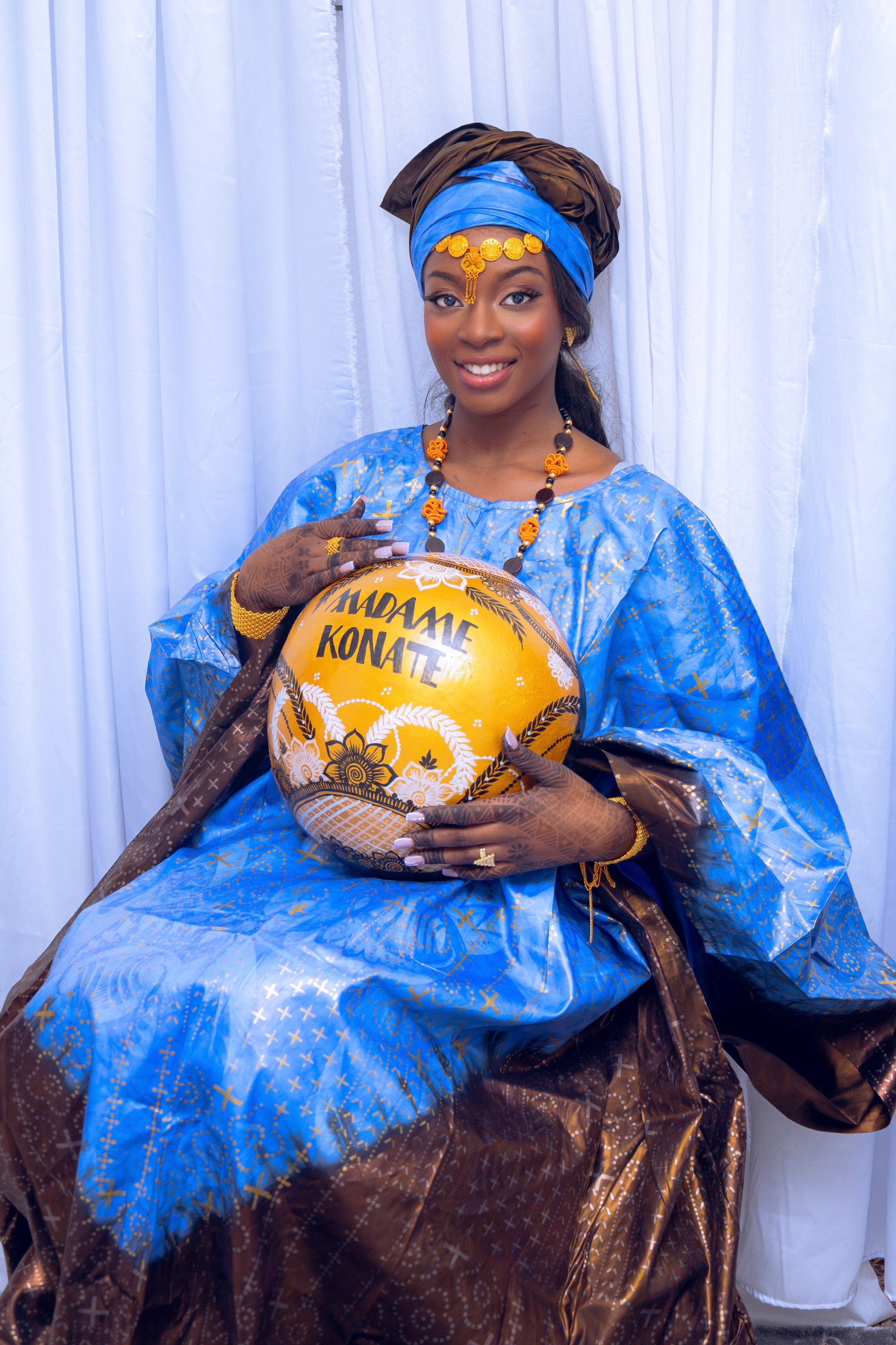Elegant African woman in blue traditional dress with a decorative pot, exuding grace and cultural richness.