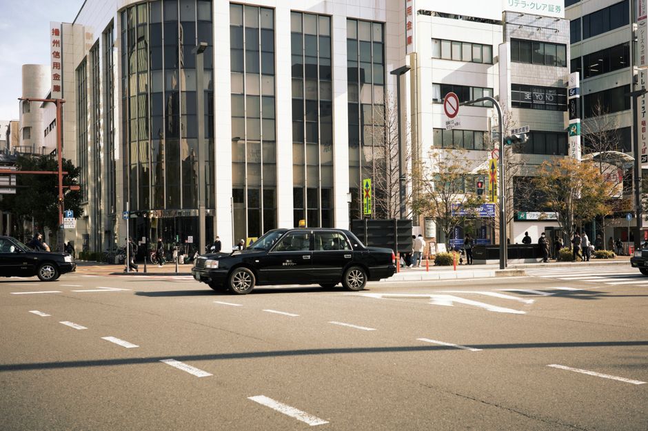 晴れた日にタクシーと近代的な建物が並ぶ賑やかな街の交差点。