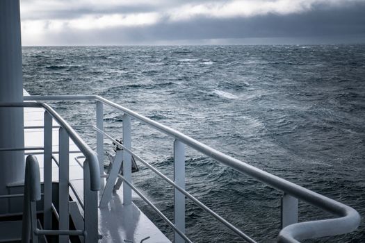 Dramatic sea view during stormy weather from a ship's deck, showcasing turbulent waters.