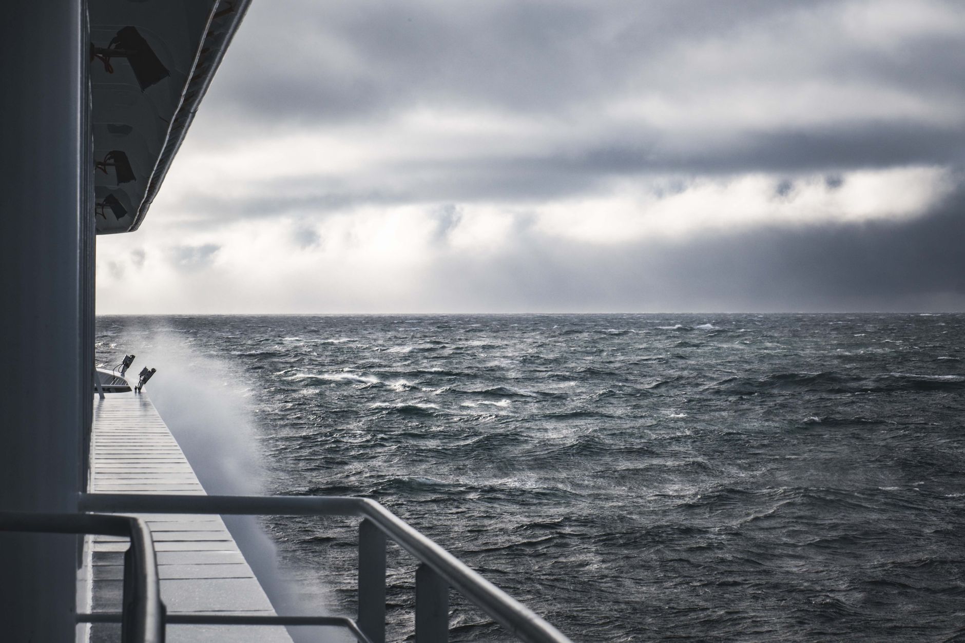 Dramatic scene of ocean waves and cloudy skies from a ship's perspective.
