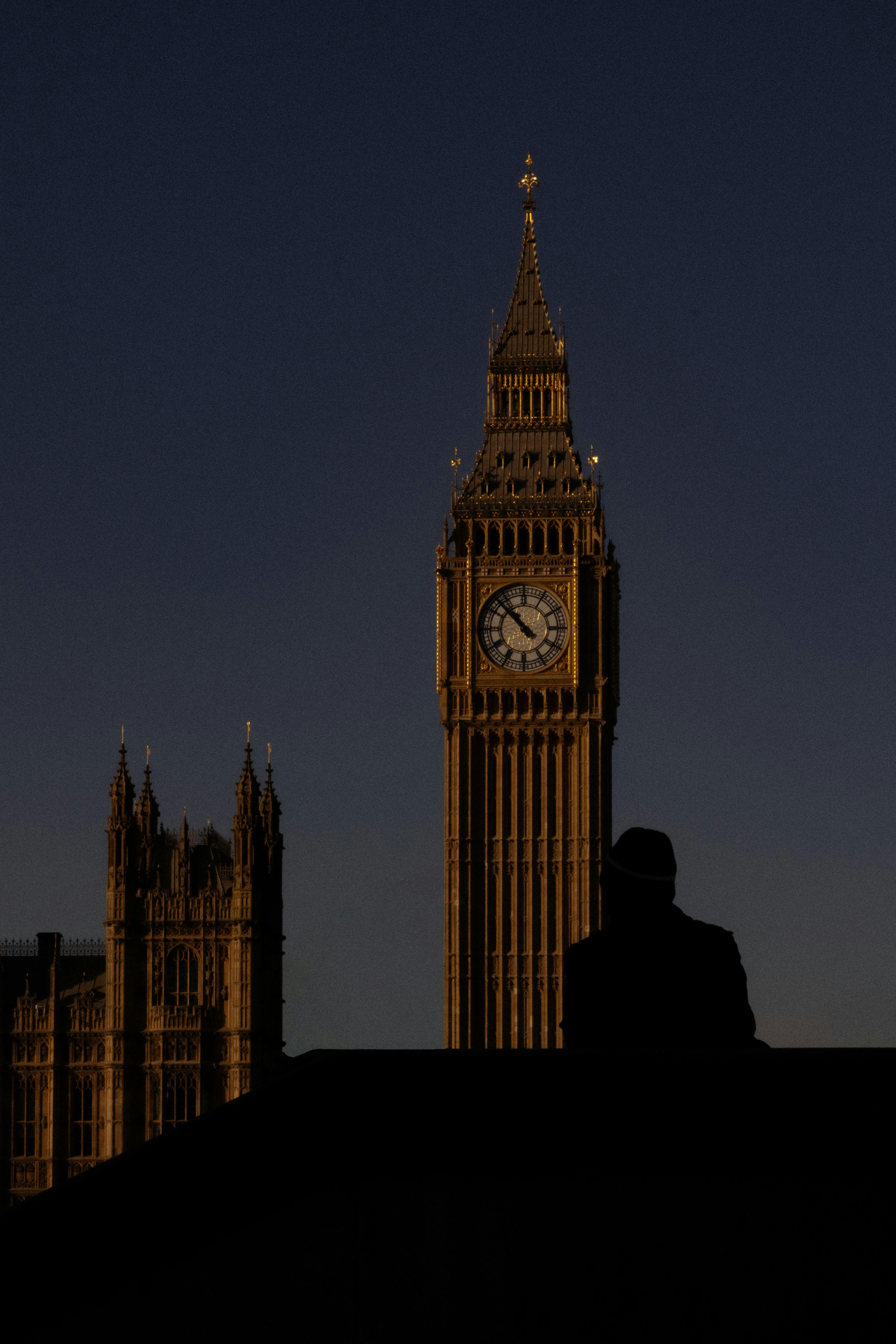 A dramatic silhouette of Big Ben against a dark evening sky in London, England.