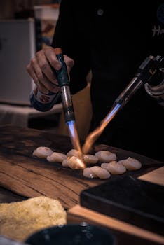 Chef using torches to flame cook scallops in Pingtung, Taiwan kitchen.