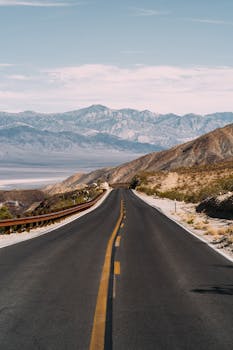 A picturesque highway winding through a desert landscape with distant mountains in the background.
